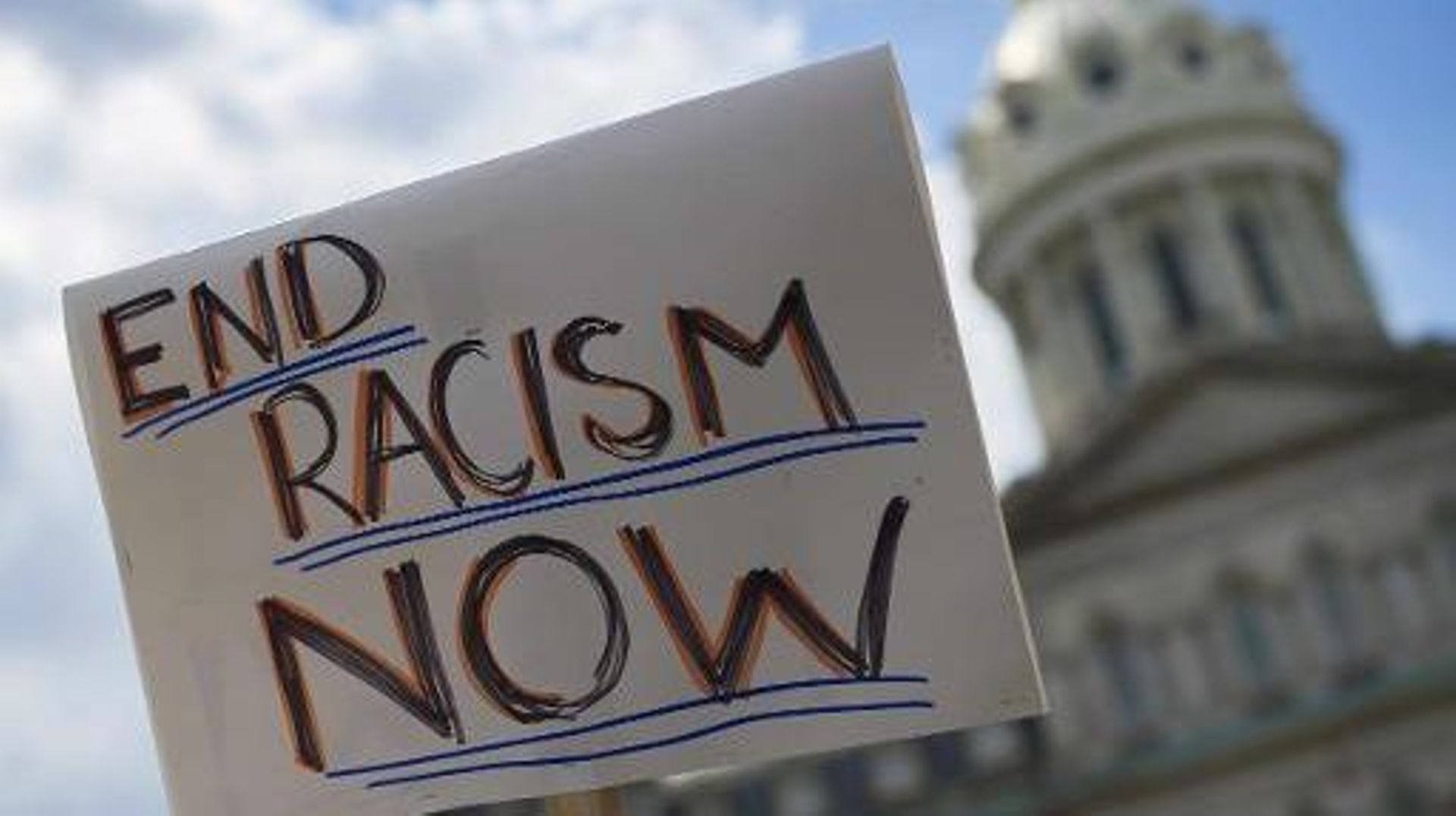 Une pancarte appellant à mettre fin au racisme est brandi devant la mairie de Baltimore dans le cadre de la manifestation pour dénoncer les brutalités policières, le 2 mai 2015