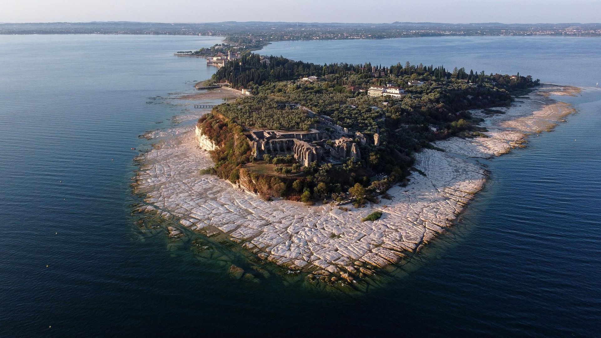 Une vue aérienne prise le 16 août 2022 montre la péninsule de Sirmione sur le lac de Garde, dans le nord de l’Italie, alors que les eaux du lac se retirent en raison d’une grave sécheresse.