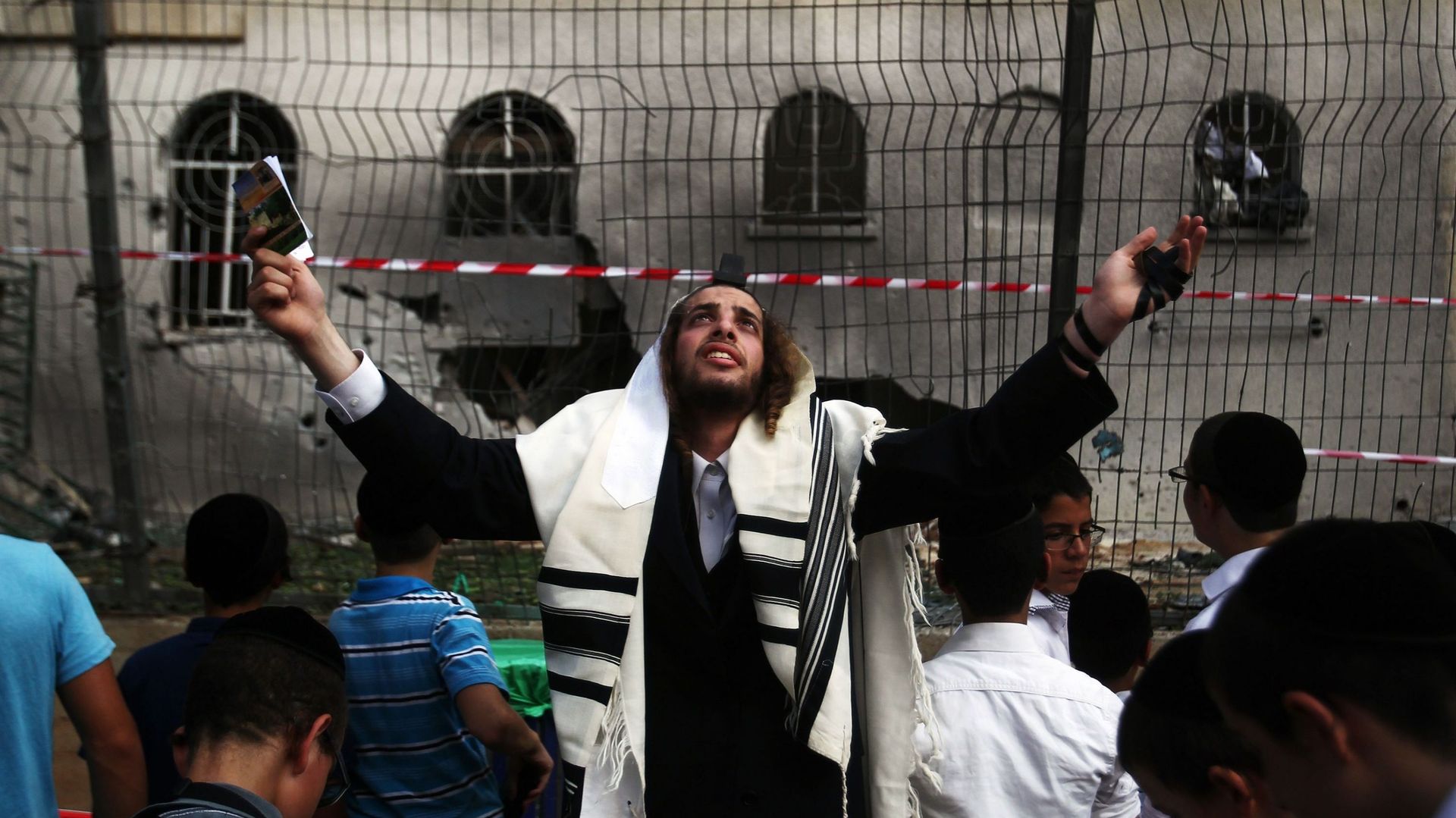Des Juifs prient devant une synagogue touchée par une roquette tirée depuis la bande de Gaza