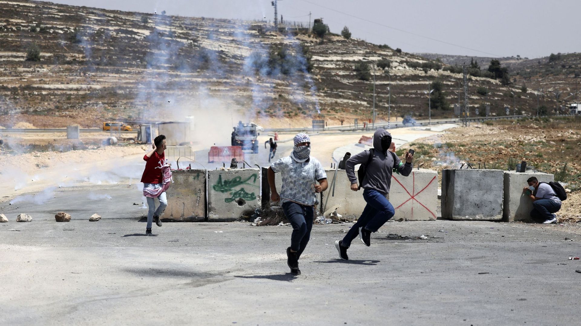 Des étudiants palestiniens fuient les gaz lacrymogènes alors qu’ils affrontent les forces de sécurité israéliennes à l’entrée nord de la ville de Ramallah, en Cisjordanie, lors d’une manifestation contre l’attaque israélienne en cours sur Gaza, le 6 août 
