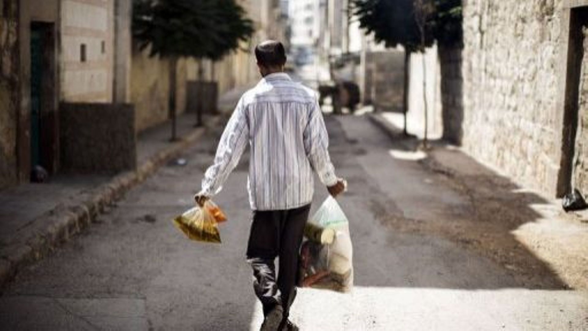 Un homme porte des sacs de dons alimentaires dans le centre d'Alep, en Syrie, le 4 décembre 2012