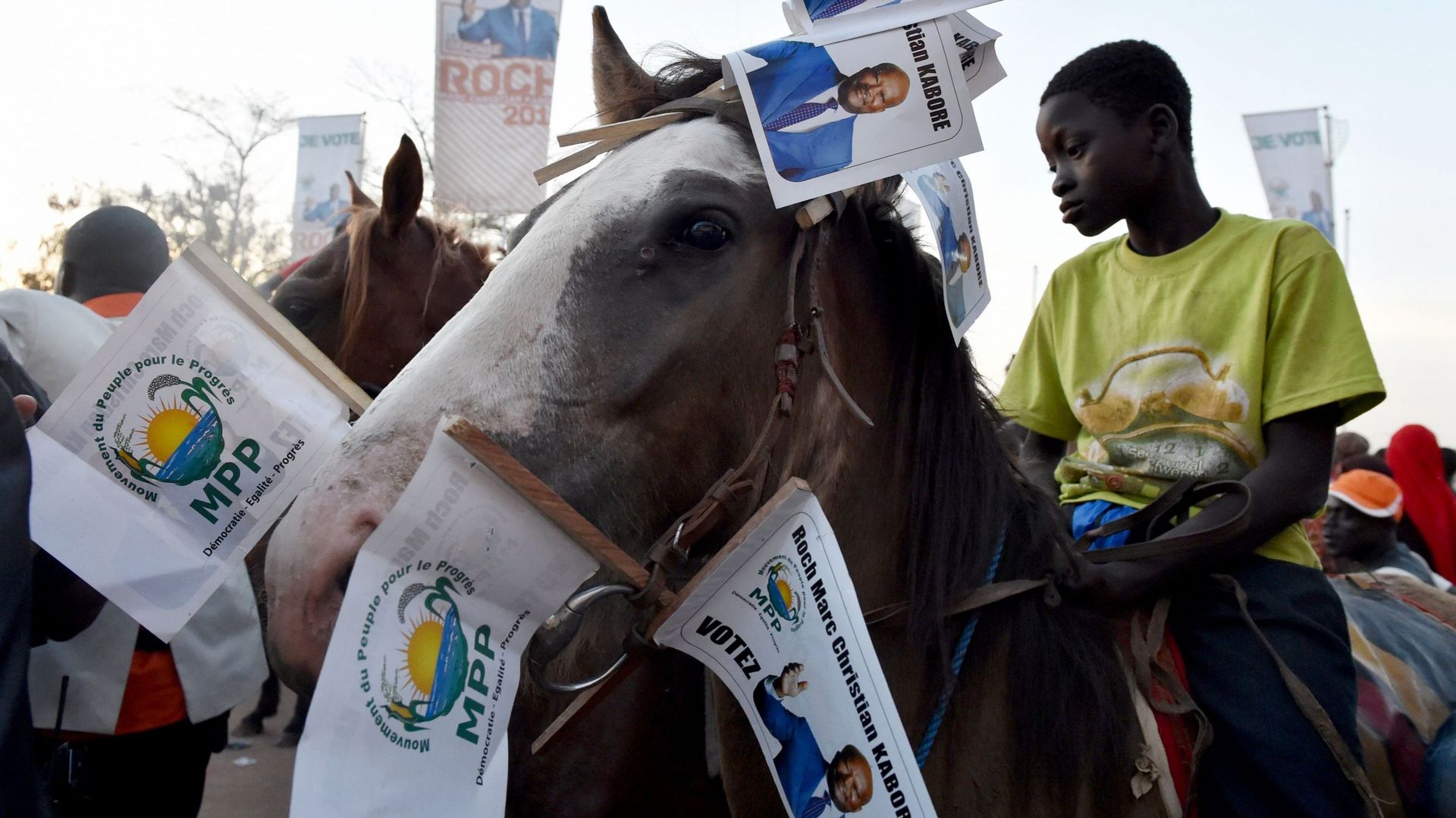Un jeune garçon à cheval arbore des drapeaux à effigie de Kaboré lors d'un rassemblement à Ouagadougou.