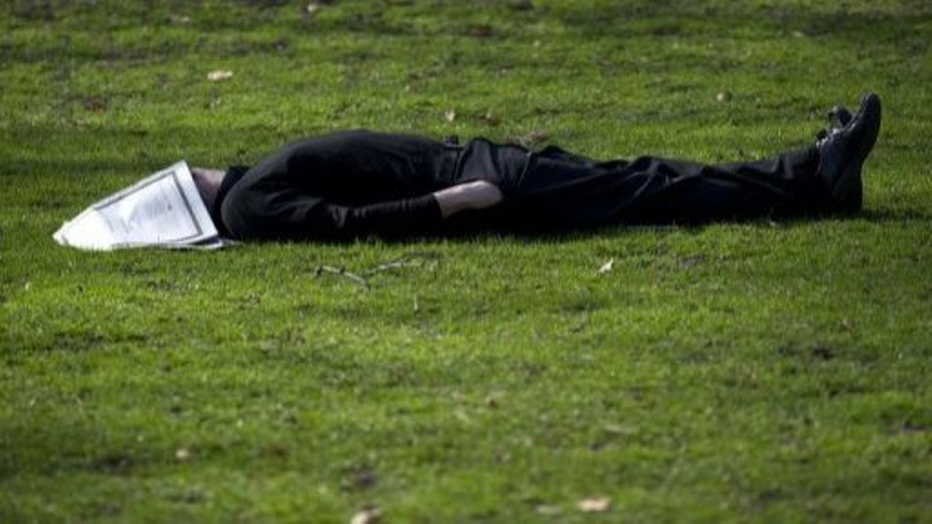 Un homme dort dans l'herbe, dans un parc londonien le 15 mars 2012