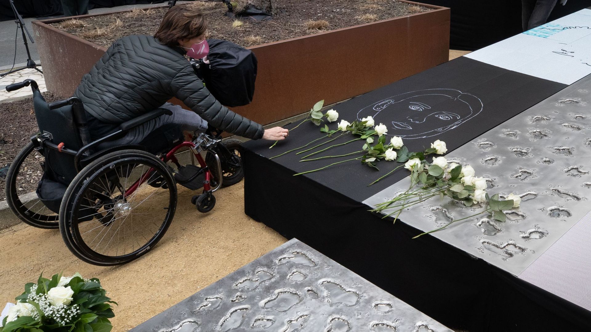 une victime dépose une rose blanche sur le monument, lors d'une cérémonie au monument aux victimes des attentats terroristes de 2016 à Bruxelles, lundi 22 mars 2021 à la Wetstraat. 