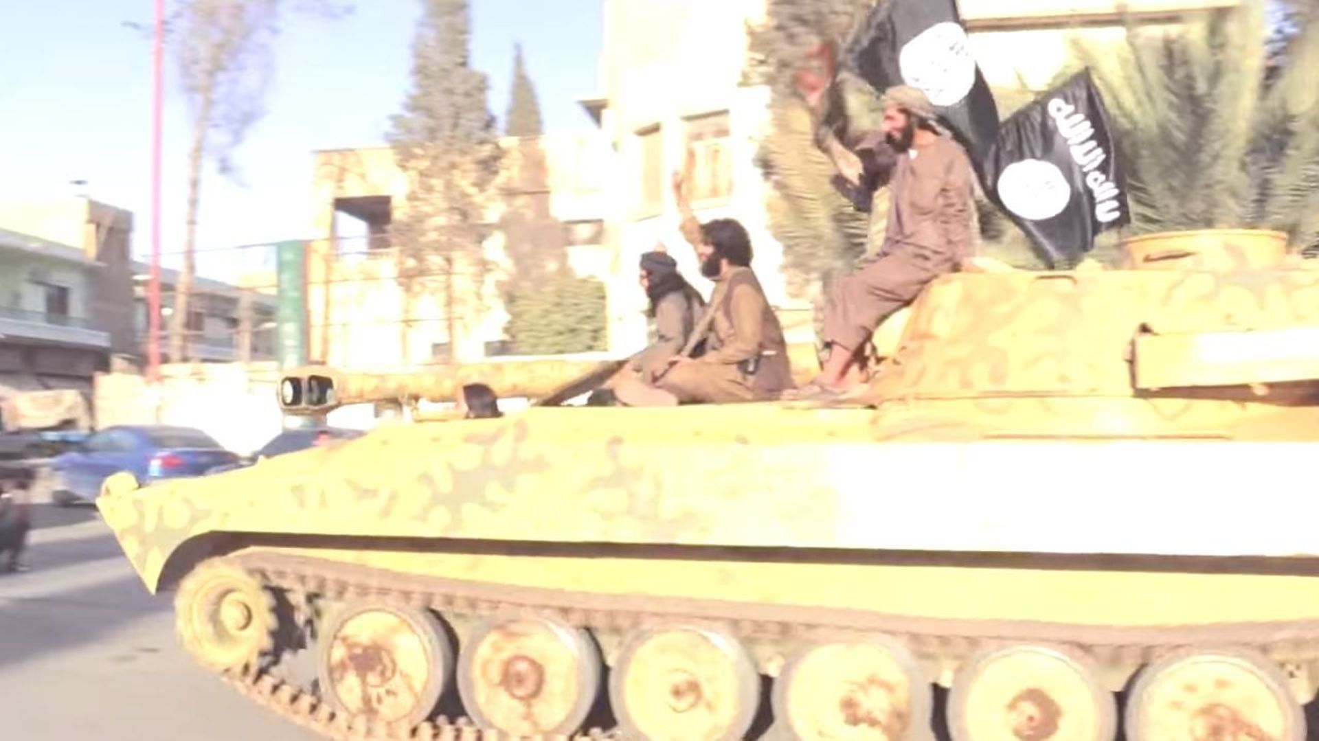 Des combattants de l'EIIL paradent sur un char saisi lors des combats en Irak