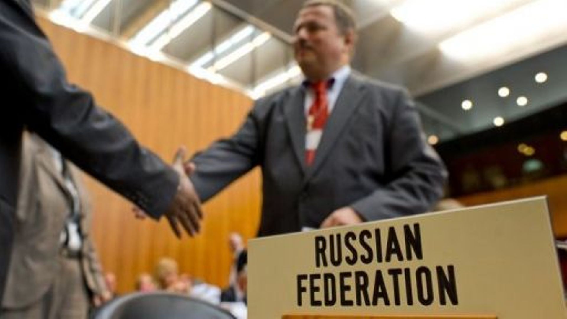 Le négociateur russe Maxim Medvedkov (d) échange une poignée de mains au siège de l'OMC à Genève lors de négociations sur l'adhésion de son pays, le 10 novembre 2011