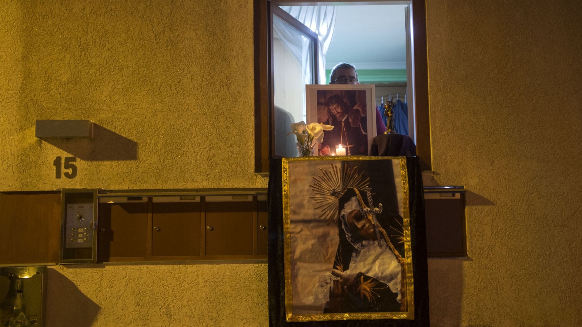Cambados - Espagne. Un homme tient une image pieuse à la fenêtre de son appartement pour célébrer le vendredi saint.
