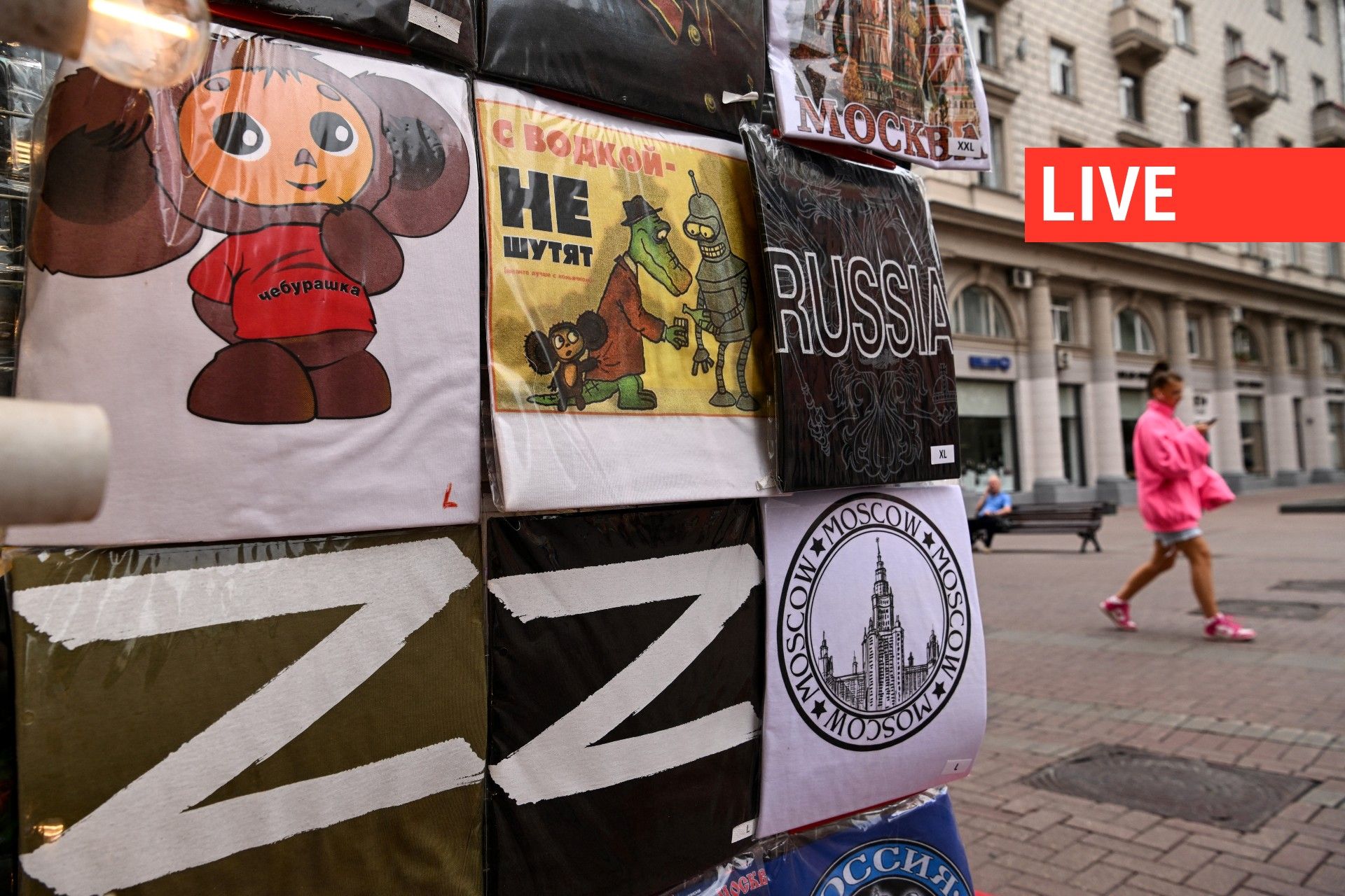 Une femme passe devant une boutique de cadeaux dans le centre de Moscou, le 8 août 2022, avec des T-shirts dont certains portent la lettre Z, un insigne tactique des troupes russes en Ukraine. Le "Z", qui est devenu un symbole de soutien à l'action milita